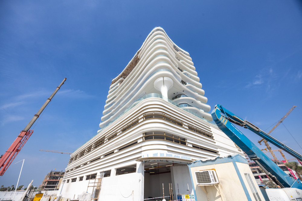 Beach Walk Residence A modern, multi-story building under construction, featuring curved architecture and construction equipment nearby.